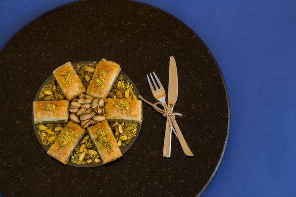 Geleneksel Türk Tatlısı Pistachio Baklava koyu mermer masa, mavi yüzey, üst manzara