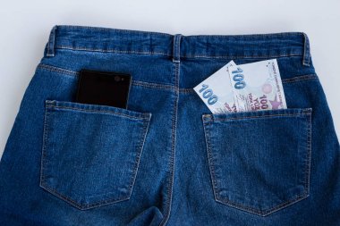 İki yüz Türk kağıt parası ve cebinde mavi kot pantolonu olan siyah ekranlı cep telefonu