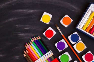 Renkli suluboya seti, tebeşir tozlu siyah arkaplan üzerindeki kalemler ve kalemler fırçayla. Eğitim kavramı