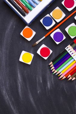 Renkli suluboya seti, tebeşir tozlu siyah arkaplan üzerindeki kalemler ve kalemler fırçayla. Eğitim kavramı