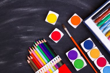 Renkli suluboya seti, tebeşir tozlu siyah arkaplan üzerindeki kalemler ve kalemler fırçayla. Eğitim kavramı