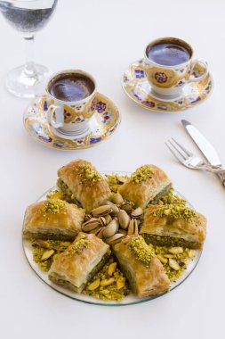 Geleneksel Türk Pastası Tatlısı Pistachio Baklava beyaz üzerine Türk Kahvesi ve çatal bıçak takımı .