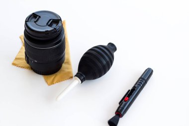 Beyaz yüzeyde fırça, pompa ve yumuşak bez ile kamera merceği temizleme kiti