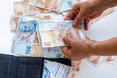 Beyaz arka planda, siyah renkli cüzdanda Türk Kağıt Parasını tutan eski el.