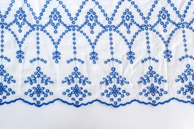 Mavi işlemeli beyaz kadın yazlık bluzunu beyaz yüzeyde.