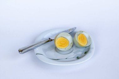 Çürük ve kaynatılmış sağlıksız yumurta tabakta bıçakla dilimlenmiş.