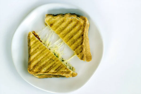 A grilled sandwich of melting cheese, on a white plate.