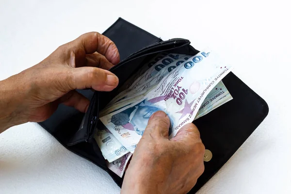 El, beyaz arka planda kimliği belirsiz yaşlı bir adamın paralarını sayıyor.