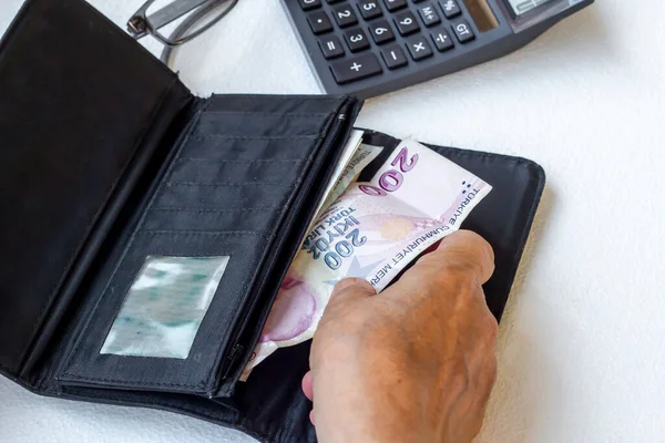 El, beyaz arka planda kimliği belirsiz yaşlı bir adamın paralarını sayıyor.