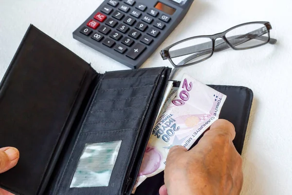 El, beyaz arka planda kimliği belirsiz yaşlı bir adamın paralarını sayıyor.