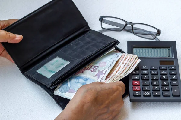 El, beyaz arka planda kimliği belirsiz yaşlı bir adamın paralarını sayıyor.