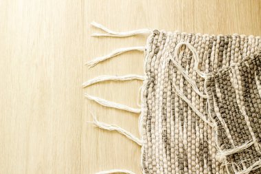 Ahşap zeminde el yapımı, gri ve beyaz tonlarda halı.