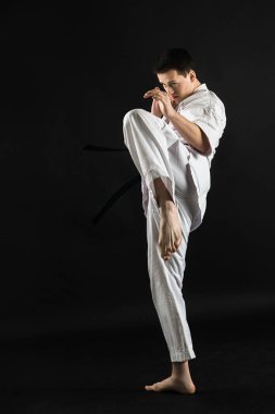 Bir karateka vurur ya da bir duruşta durur. Dövüş sanatları. Shidokan karatesi. Stüdyoda dövüşçü var. Siyah arka planda kimonolu adam. Yumruk at. Tekmele. Dünya Karate Birliği, Shidokan. Kara kuşak karate.