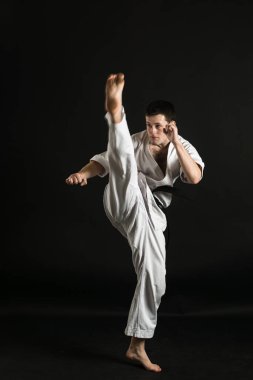 Bir karateka vurur ya da bir duruşta durur. Dövüş sanatları. Shidokan karatesi. Stüdyoda dövüşçü var. Siyah arka planda kimonolu adam. Yumruk at. Tekmele. Dünya Karate Birliği, Shidokan. Kara kuşak karate.