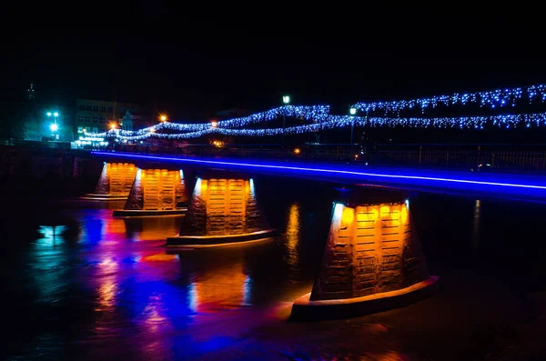 Gece şehri uzun süre fotoğraflandı. Su, parıltı ve gece lambaları. Uzhgorod şehrinin mimarisi ve binaları. İnsansız güzel gece fotoğrafları. Sokakta kimse yok.