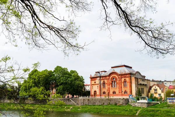 Uzhgorod şehrindeki Transcarpathian Bölgesel Filarmoni Topluluğu. Bina romantik, vizantian ve Mauritian tarzında kırmızıdır. Sinagog. Bahar ya da Yaz. Ağaçlar ve çimenler yeşildir