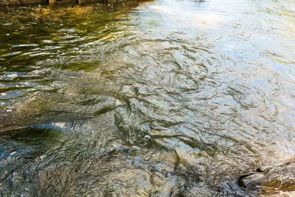 Su dokusu. Dağ nehri. Yeşil, mavi ve gri dalgalar. Sakinlik ve sükunet. Doğa. Bir park. Nehir kıyısındaki taşlar. Suyun hızlı akışı