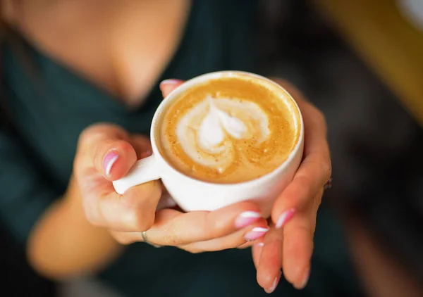 Bir fincan kahve, kapuçino, kadınların elinde latte.