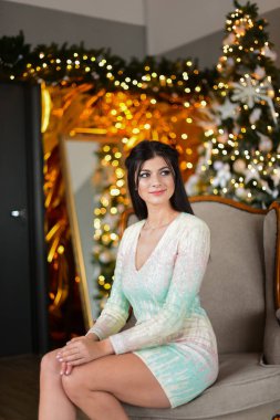 Noel ağacının yanındaki Noel odasında sandalyede oturan güzel bayan ve büyük saat.