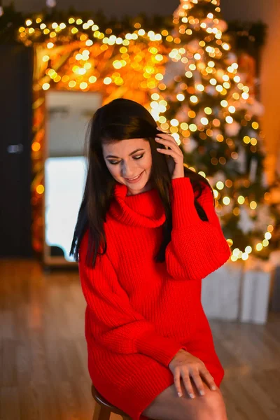 In Christmas room, beautiful young girl, with dark hair, wearing in red Christmas sweater. — Stock Photo, Image