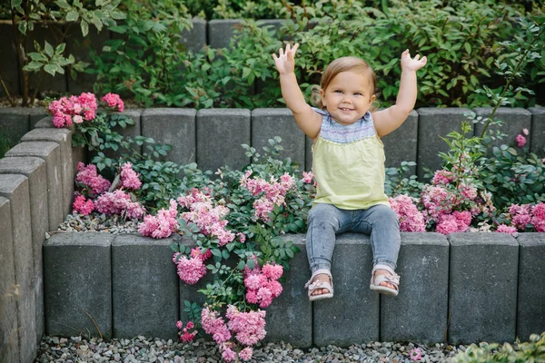 Baby-Mädchen vor Spielplatz lacht in Blumen — Stockfoto