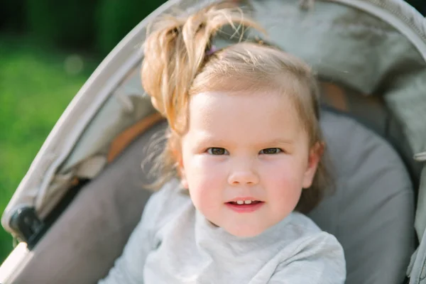 Bébé fille dehors assis dans une poussette — Photo