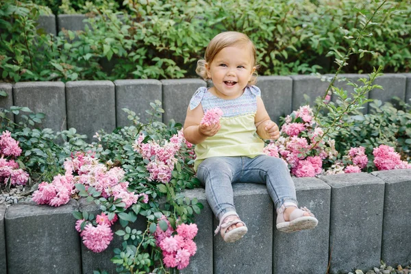 Μωρό κορίτσι έξω παιδική χαρά γελώντας στα λουλούδια — Φωτογραφία Αρχείου