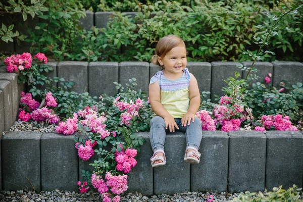 Μωρό κορίτσι έξω παιδική χαρά γελώντας στα λουλούδια — Φωτογραφία Αρχείου