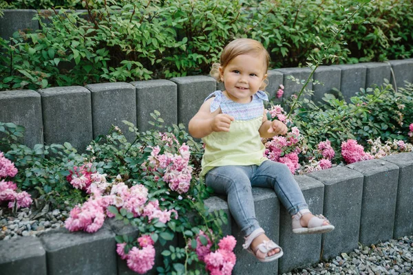 Bébé fille dehors aire de jeux riant dans les fleurs — Photo