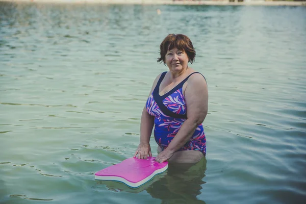 Mujer mayor activa con tabla de natación en el agua — Foto de Stock
