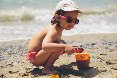 Kum oyuncakları ile plajda oynayan 3 yaşındaki kız