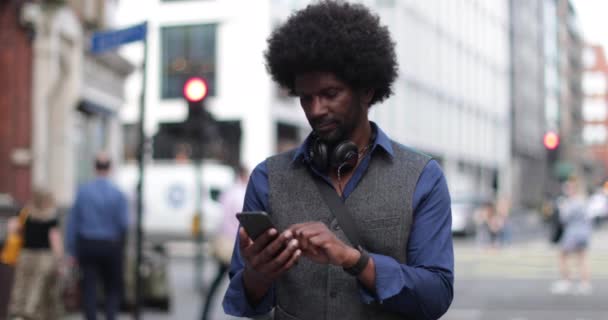 Портрет афроамериканского мужчины на улице со смартфоном — стоковое видео
