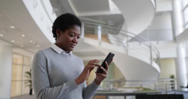 Afro-americano usando smartphone no escritório moderno — Vídeo de Stock