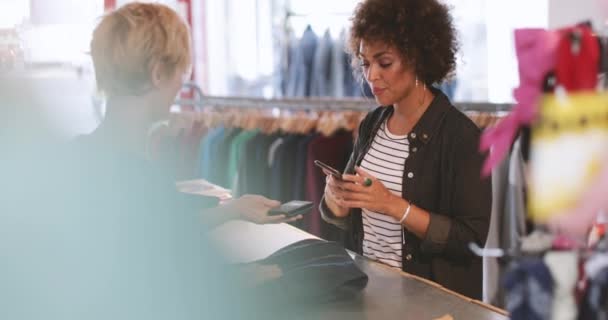 Klant betaalt voor kleding bij de kassa — Stockvideo