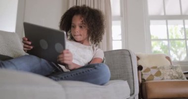 Afro-Amerikan kız dijital tablet evde kanepe üzerinde oyun oynamak