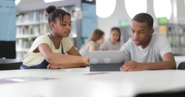 Kitaplığa bir dijital tablet ile birlikte eğitim lise öğrencileri