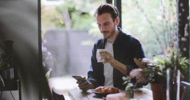 Yetişkin erkek Smartphone mutfakta kahve bir fincan ile kontrol