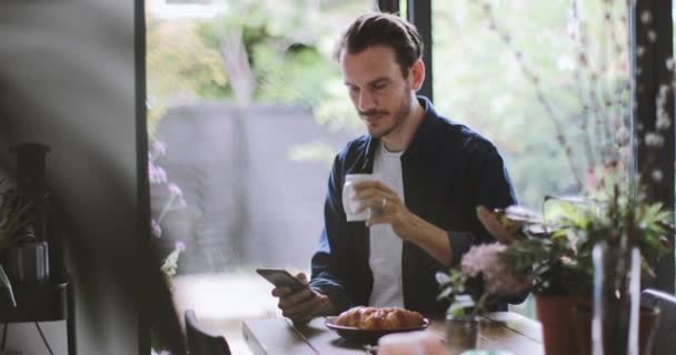 Hombre Adulto Chequeando Smartphone Cocina Con Taza Café — Vídeos de Stock