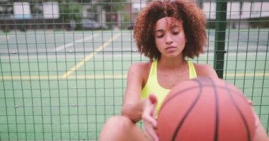 Bir basketbol sahası üzerinde oturan genç yetişkin kadın