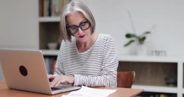Olgun yetişkin kadın bir dizüstü bilgisayar kullanarak online fatura ödeme