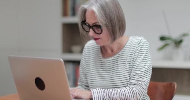 Olgun yetişkin kadın bir dizüstü bilgisayar kullanarak online fatura ödeme