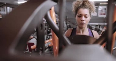 Spor salonunda ağırlık makinede çalışan güçlü kadın
