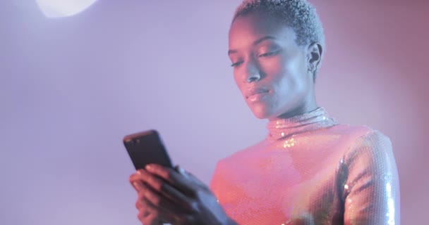 Kobieta w kolorowe jasne światła, patrząc na smart phone — Wideo stockowe