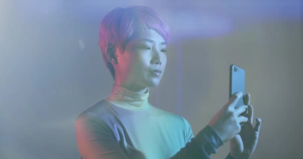 Asiatin nutzt Smartphone in futuristischer Umgebung — Stockvideo