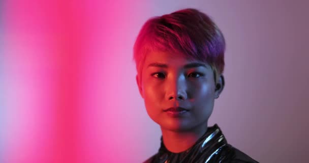 Portrait of trendy Asian gender fluid person looking to camera with neon lights — Stock Footage Portrait of trendy Asian gender fluid person looking to camera with neon lights — Stock Video