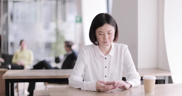 Affärskvinna på ett kafé med en smartphone — Stockvideo