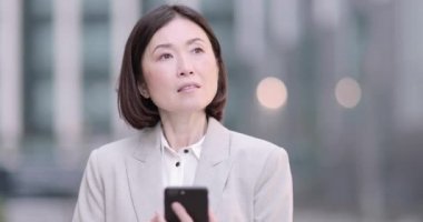 İş kadını akıllı telefon kullanarak şehirde açık havada