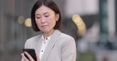İş kadını akıllı telefon kullanarak şehirde açık havada