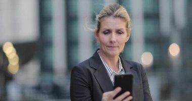 İş kadını akıllı telefon kullanarak şehirde açık havada