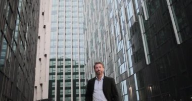 İşadamı akıllı telefon kullanarak şehirde yürüyor